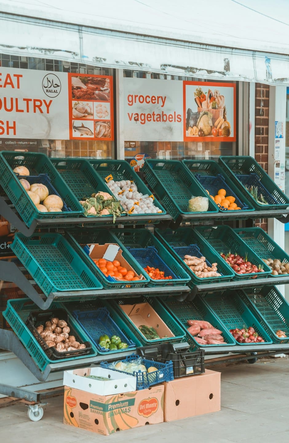Frutas y verduras frescas en cajas en la entrada de una tienda de comestibles.